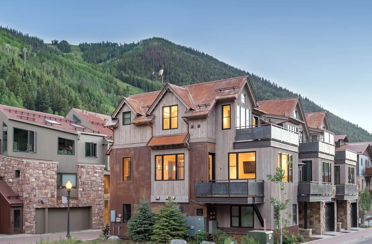 A wide shot of Ironwood A’s multi-story exterior, framed by majestic mountains and lush trees. The image showcases the home’s outdoor balconies and the surrounding scenic beauty, inviting viewers to imagine relaxing on the decks while taking in the views.