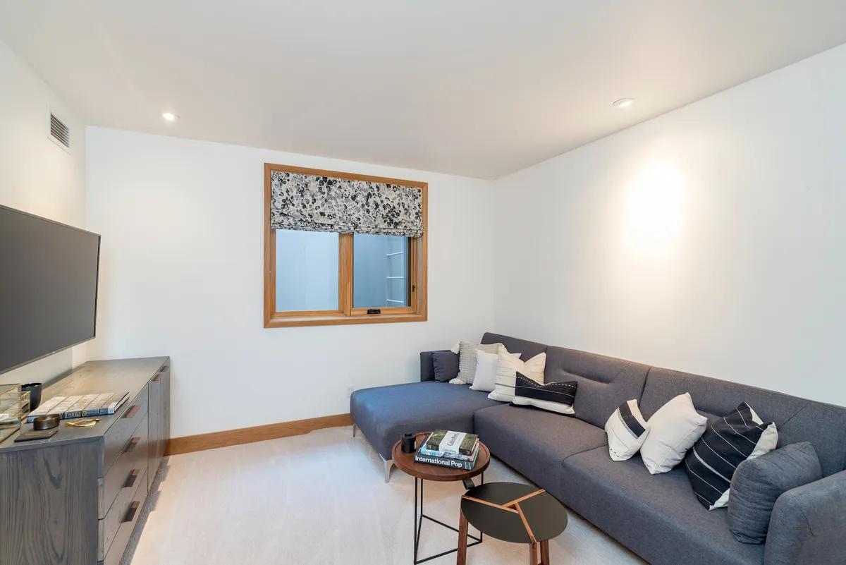A comfortable nook with a sofa, television, window, and coffee table, perfect for quiet moments, reading, or keeping kids close while relaxing.